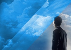 A businessman seen from behind looking up at a blue sky with clouds, symbolizing cloud computing and future vision