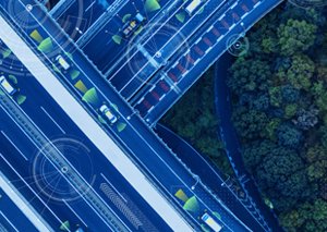 Aerial view of a highway interchange with digital overlays representing smart traffic monitoring, autonomous vehicles, and ITS analytics