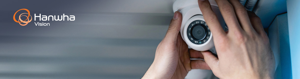 A person installing a smart security camera outside of a business.