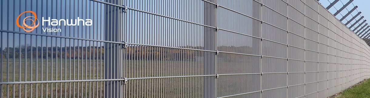 Perimeter security fence on a plain, mown area