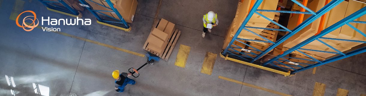 In Warehouse People Working, Forklift Truck Operator Lifts Pallet with Cardboard Box.