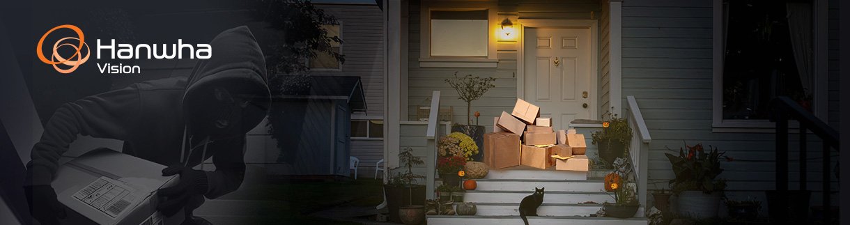 BL_S_63_Holiday-Shopping-2025-v1-1 A stack of cardboard delivery boxes sits on the front porch of a house at night, decorated for the holiday season. On the left, a shadowy figure in a hooded sweatshirt appears to be stealing the packages.