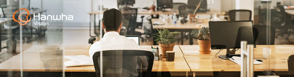A modern office space with a person sitting in a conference room in an ergonomic chair.