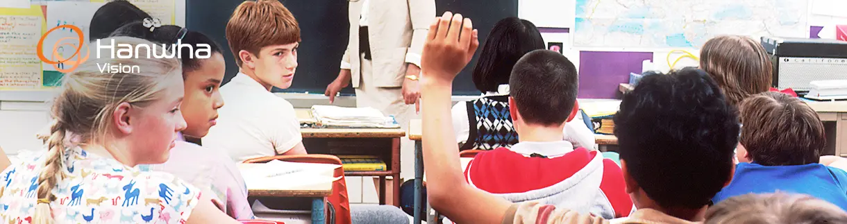 banner_1_school_B Schoolchildren sit in a classroom as one student raises their hand